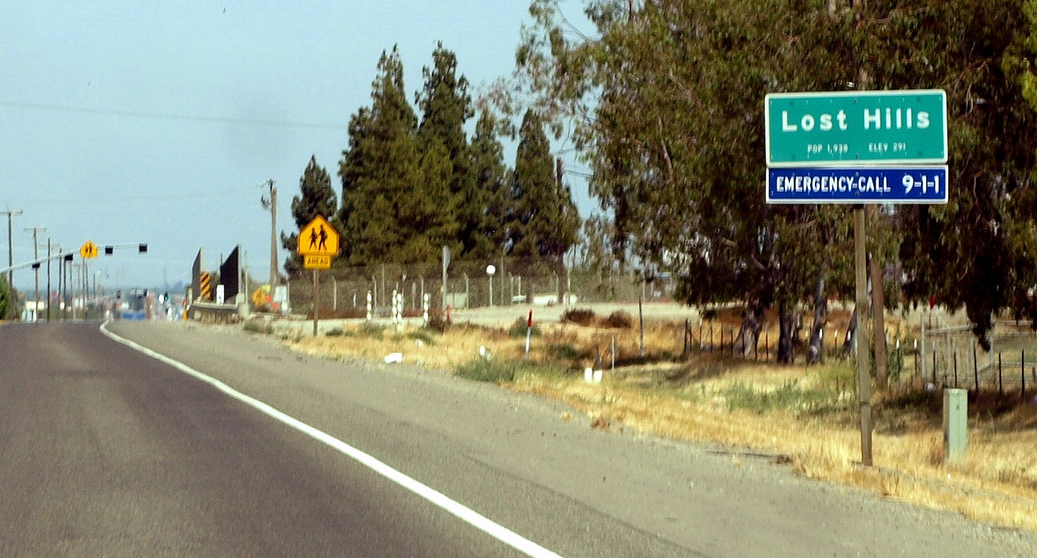 Western town limits sign for the census-designated place of Lost Hills, California as seen from the eastbound lane of State Route 46 (Paso Robles Highway) between Pavilion Way and the Governor Edmund G.