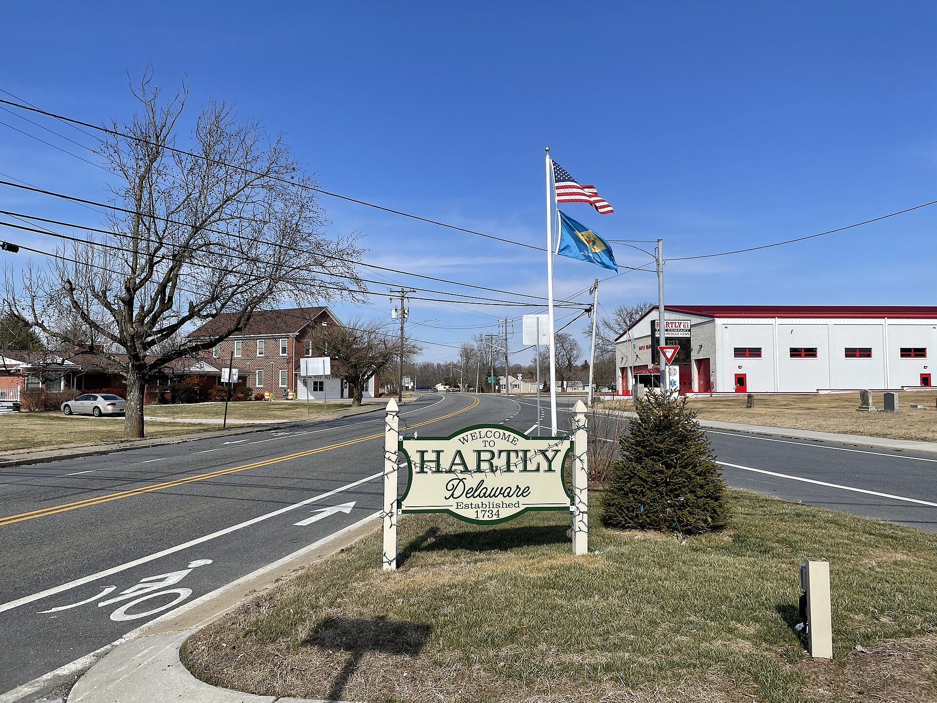 Sign for Hartly, Delaware and flagpole at the intersection of Delaware Route 11 (Arthursville Road) and Delaware Route 44 (Everetts Corner Road/Main Street)
