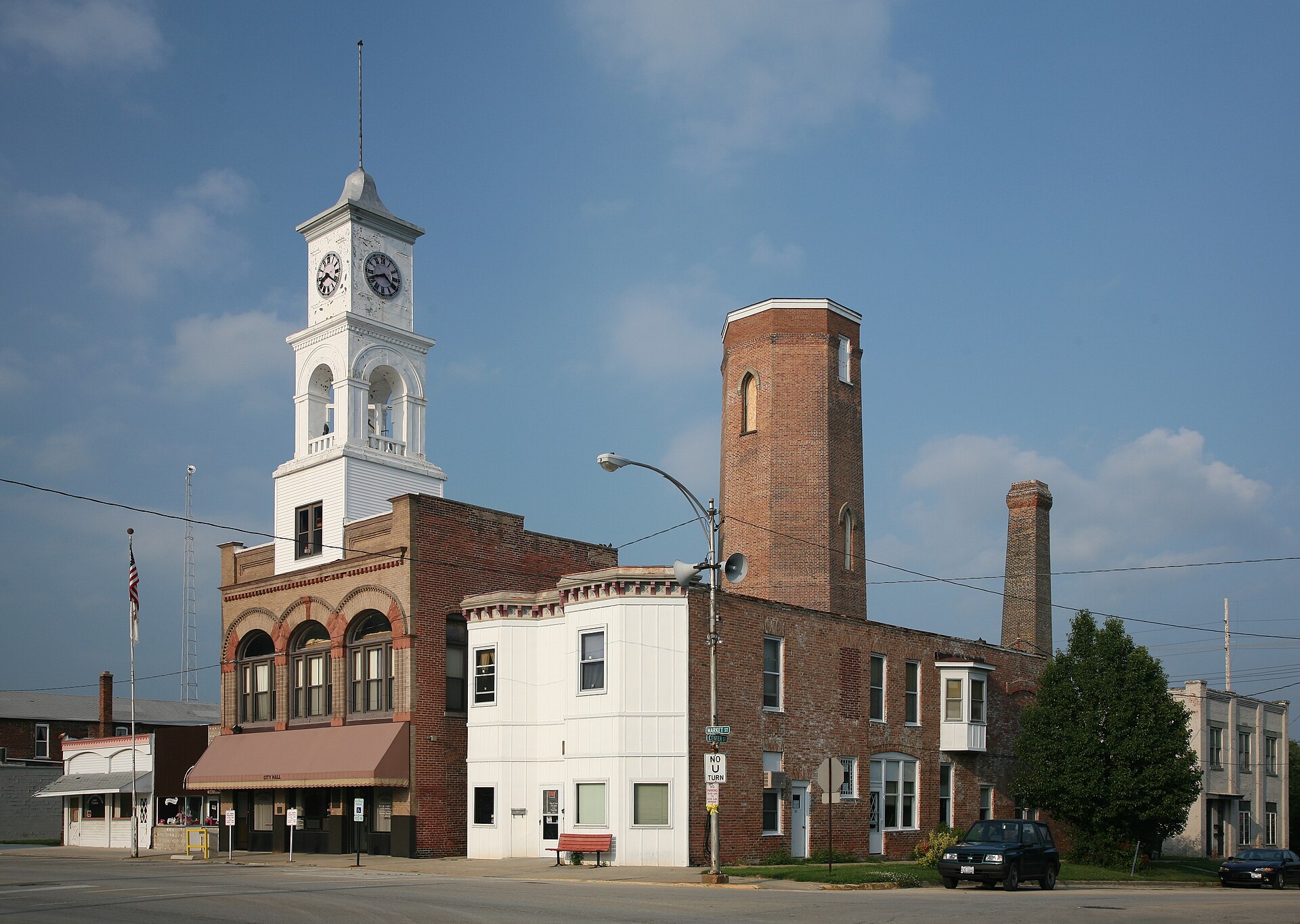 City hall in Paxton, Illinois with clock tower and historical water tower behind it.