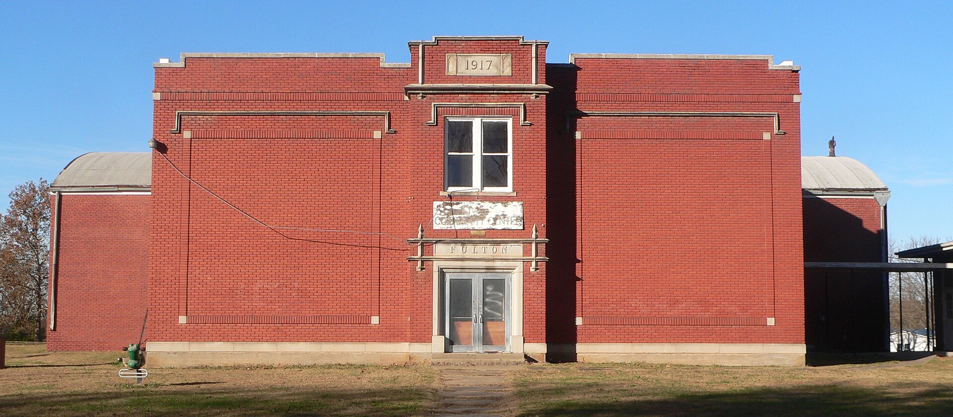 School buildings on north side of Osage Street east of Fifth Street in Fulton, Kansas; seen from the south. A third building is just out of frame to right (east).