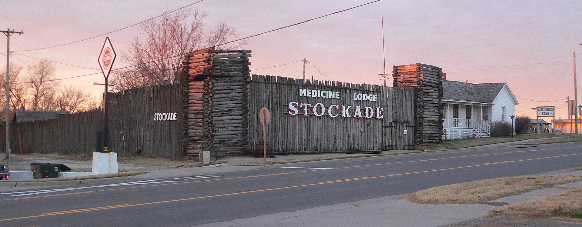 Medicine Lodge Stockade Museum (left) and Carry A. Nation house (right), on the south side of Fowler Street (U.S. Highway 160) east of Oak Street in Medicine Lodge, Kansas; seen from the northeast.