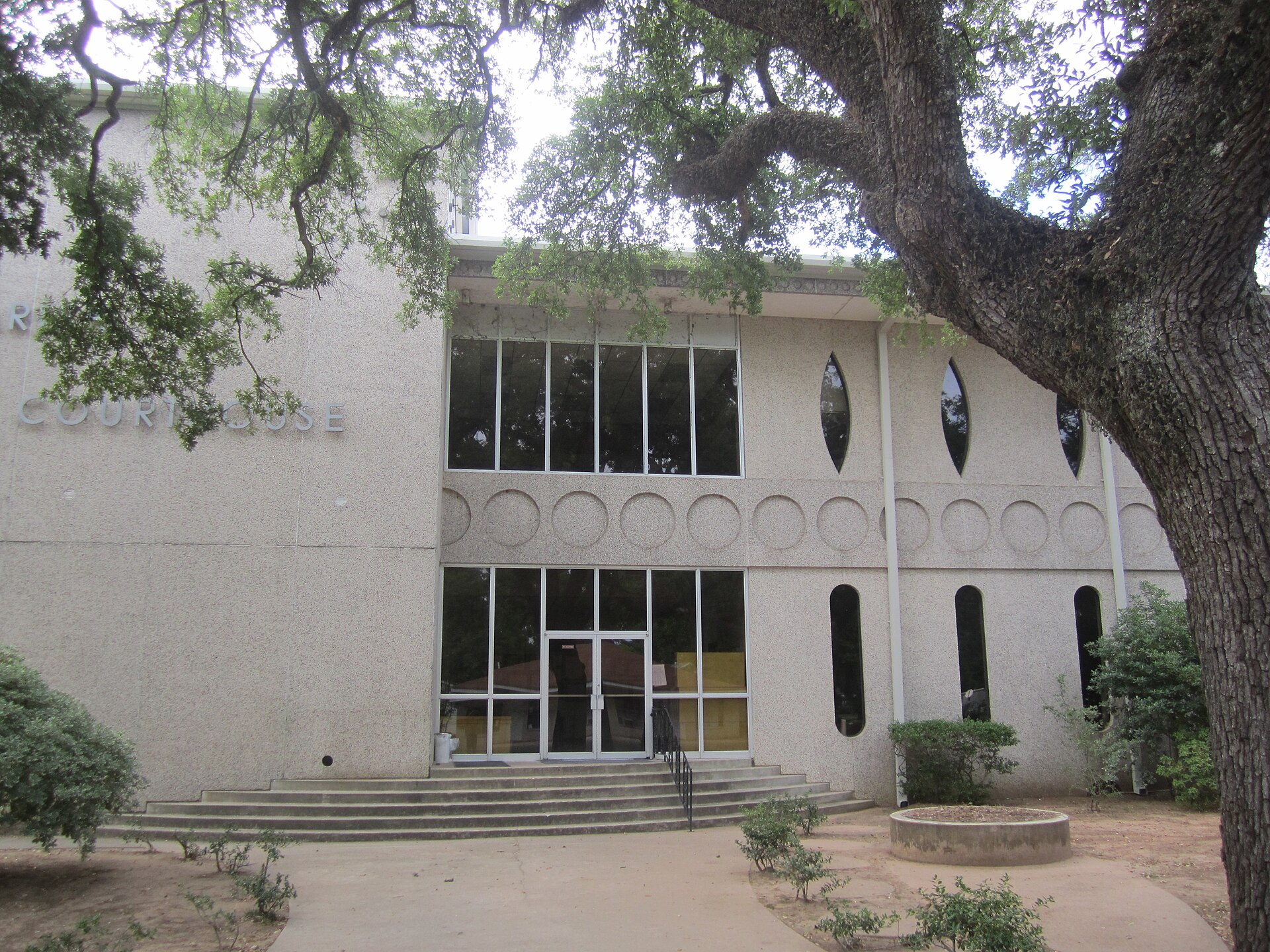 I took photo in Colfax, LA, of Grant Parish Courthouse, which is shielded by a large tree. I used a Canon camera. — Louisiana