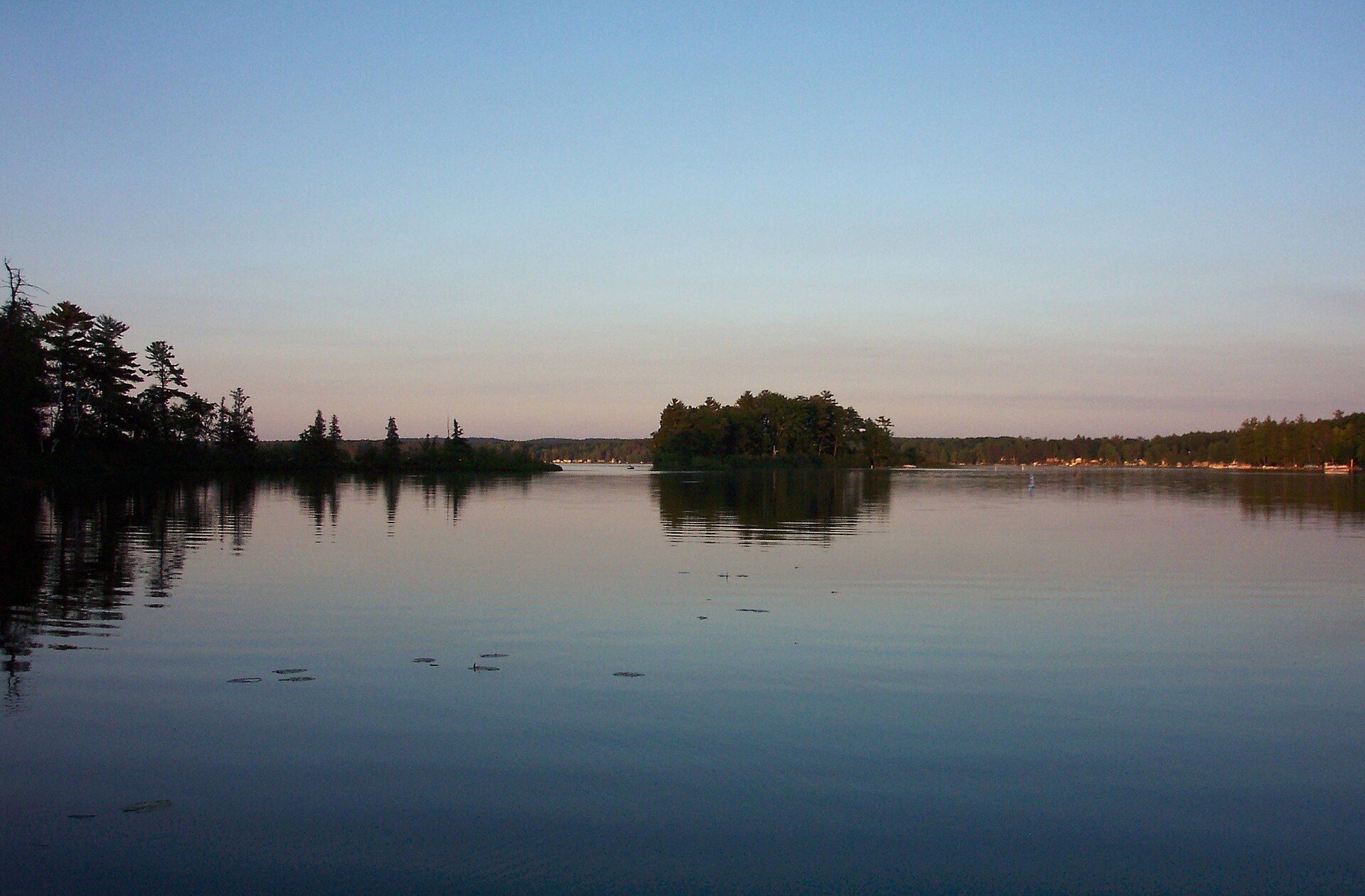 A photo of Fife Lake from the water at sunset, facing west towards Helen Island. — Michigan