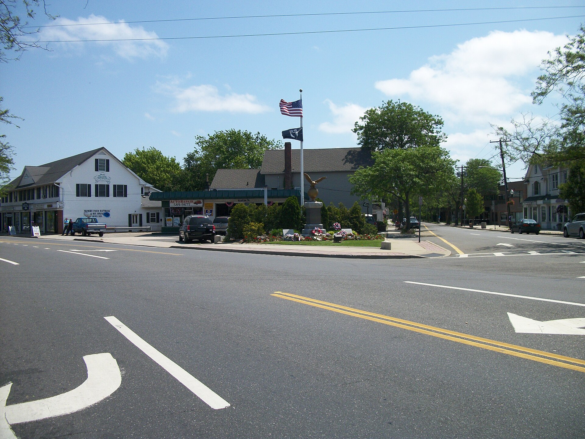 Sparrow Park War Memorial at the corner of Main Street (Suffolk County Road 85), and Middle Road (Suffolk County Road 65), in Sayville, New York. A former Gulf Gas station can also be seen behind the memorial.