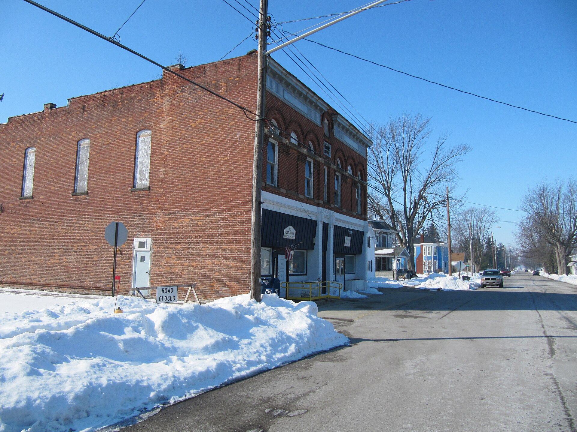 Photograph of the village of Jerry City, Ohioen, taken at street level from Main Street, looking West toward the local office of the United States Postal Serviceen.